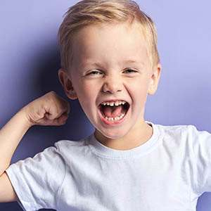 boy smiling with curled arm, pediatric dentistry baytown tx