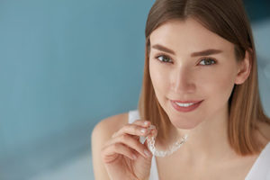 woman holding clear teeth aligner, dental braces tx