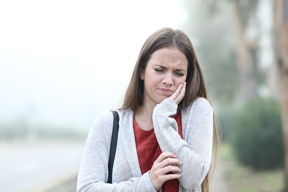 common dental problems (2) woman walking outside holding jaw experiencing common dental problems